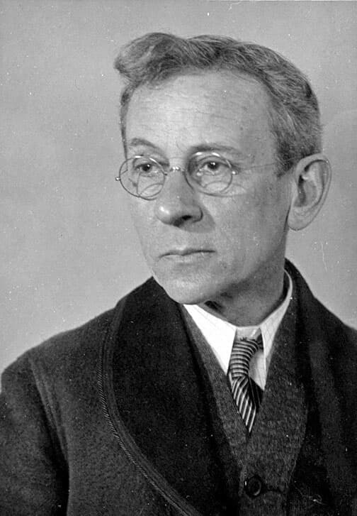 B&W portrait of Lewis Hine looking to the left wearing wireframe glasses, a tie, and a coat