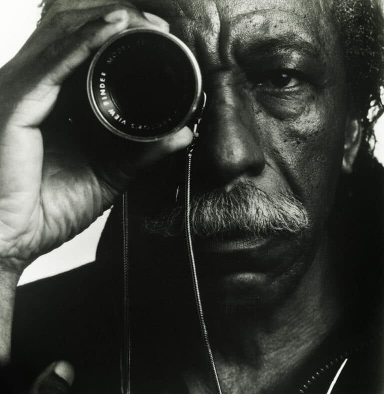 B&W portrait of Gordon Parks holding a viewfinder up to his right eye