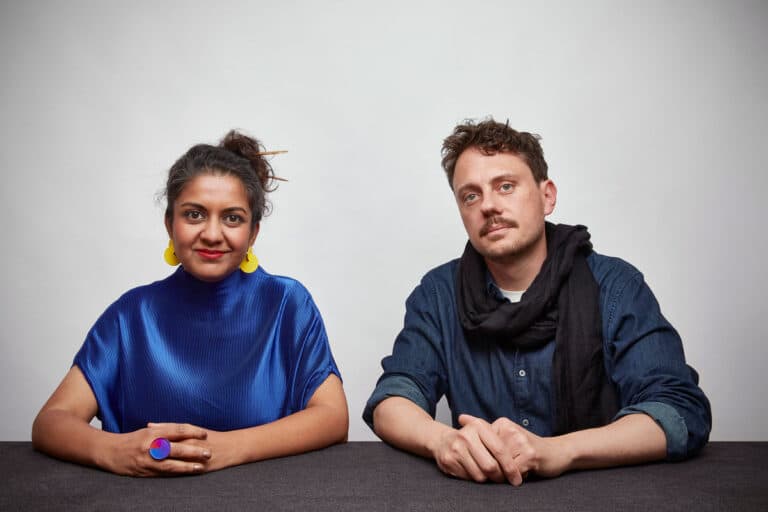 Color photo of Superflux co-founders Anab Jain, wearing blue shirt, and Jon Ardern, wearing black scarf