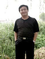 3/4 length color photo of Wang Mianli outdoors with grass in the background wearing a black shirt and pants