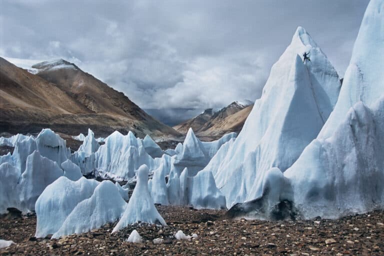 Icy blue mountain-like glaciers set in front of clouds and mountains