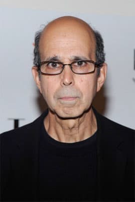 Color photo of Builder Levy looking directly into camera wearing dark framed glasses and a black shirt