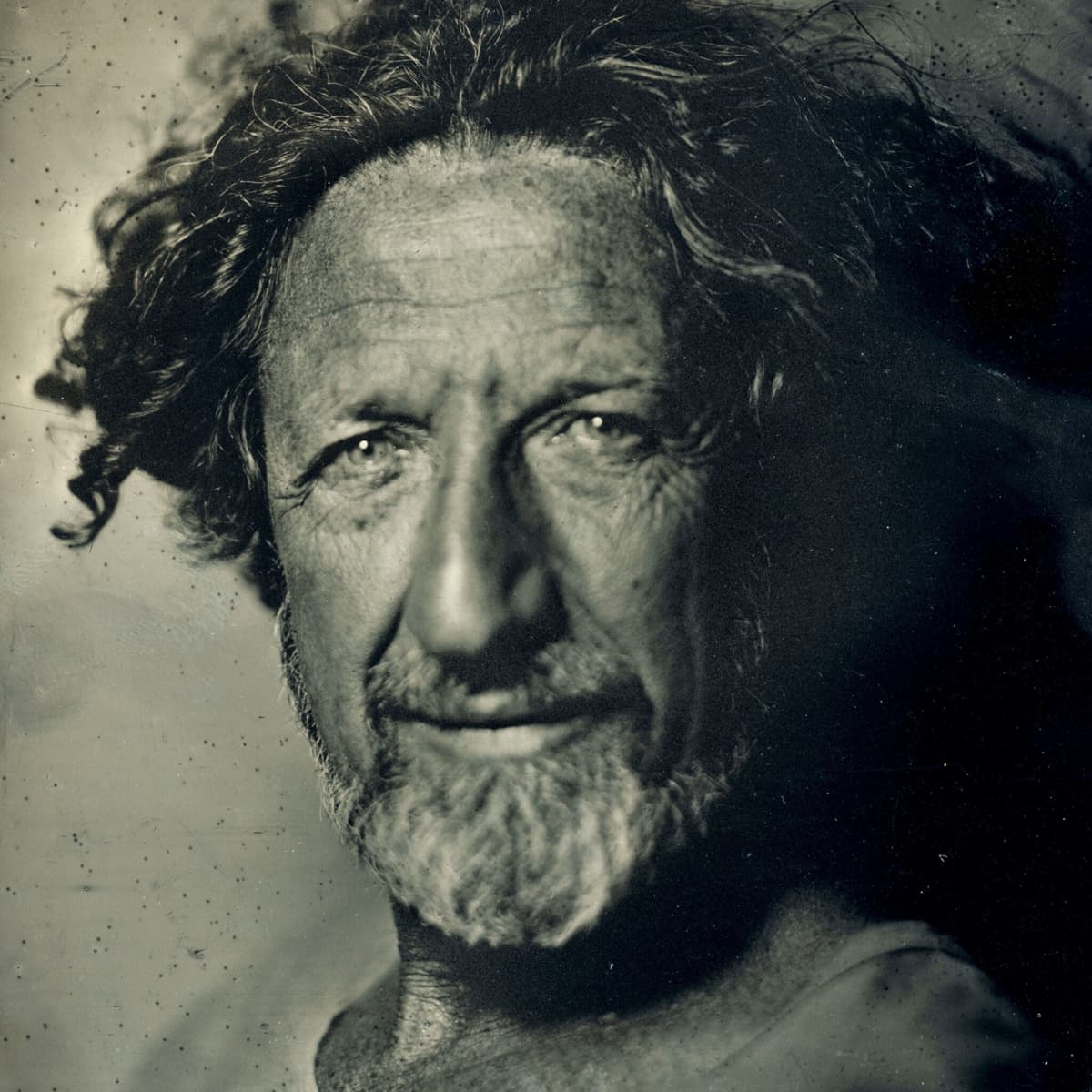 Sepia toned portrait of Gideon Mendel looking into the camera