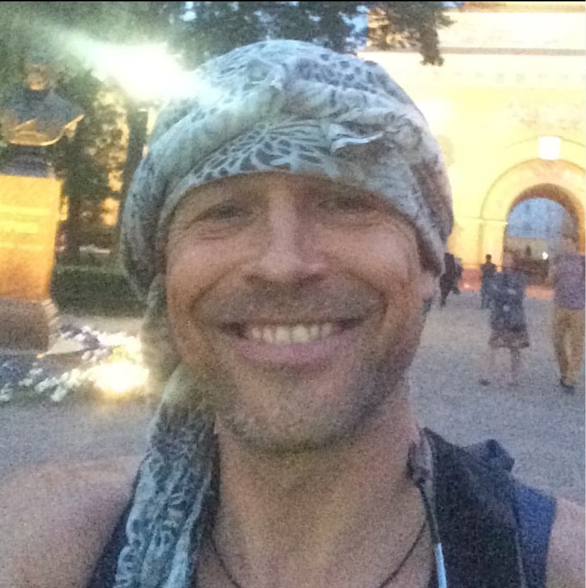 Color self portrait of Gleb Kosorukov smiling at the camera and wearing a patterned scarf on his head