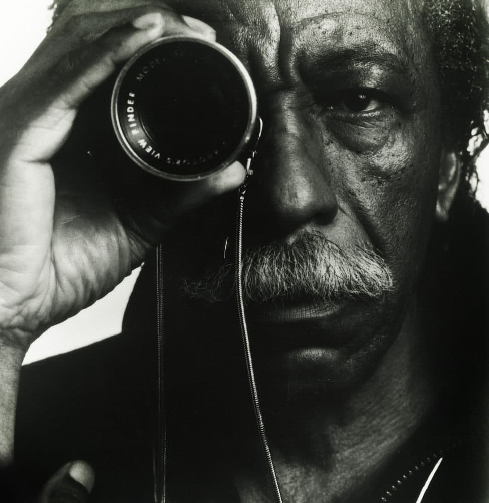 B&W portrait of Gordon Parks holding a viewfinder up to his right eye