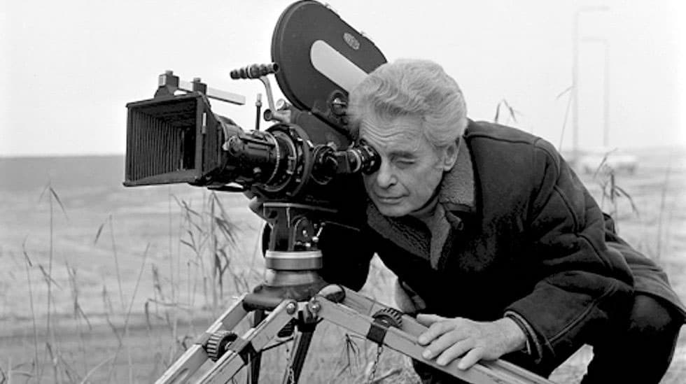 B&W photo of Joris Ivens bent over and looking into a film camera