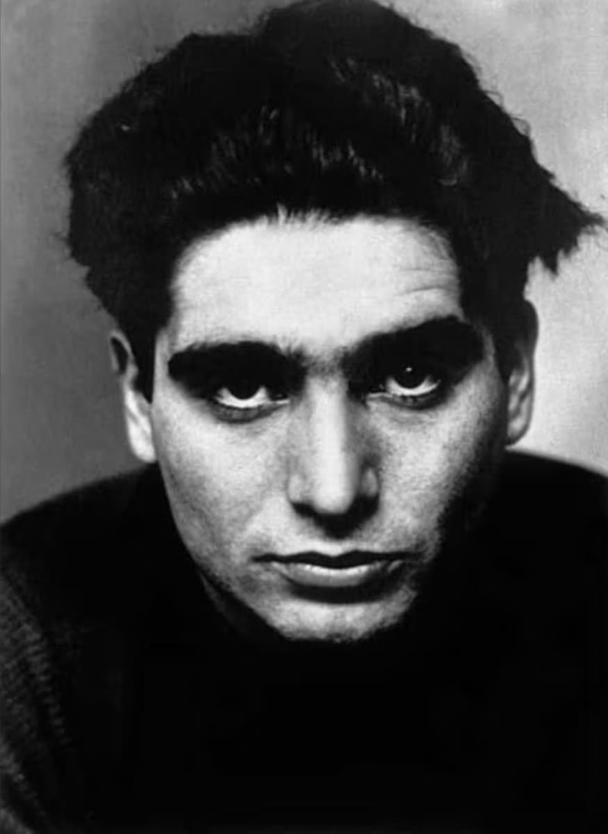 B&W portrait of Robert Capa looking directly into camera and wearing a dark shirt
